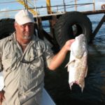 Capt. Casey Kieff holds up a red hooked — and bitten off by a shark — near a wellhead.