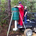 Dennis Tietje’s dad Cyrus and his son Logan place a feeder at the edge of a pine plantation where it can be seen from a corner stand.