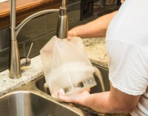 Just run a little water over the outside of the container, and the block ice drops right out.