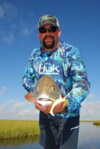 Chris Ellis, with Huk Performance and Fishing Gear, shows off a nice marsh red caught sight-fishing with Capt. Curtis LeNormand in the marshes off American Bay.