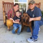 Lindsy Alcock, her son Eli, and Douglas Downs pose with Honey, a 3-year-old bloodhound who tracked Eli for a mile after he went missing on the night of Feb. 23 in Sabine Parish.