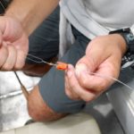 6- Use a needle made of fine stiff wire to pull the line through the cork. After the line is threaded through the cork, peg it in place with a piece of round toothpick.