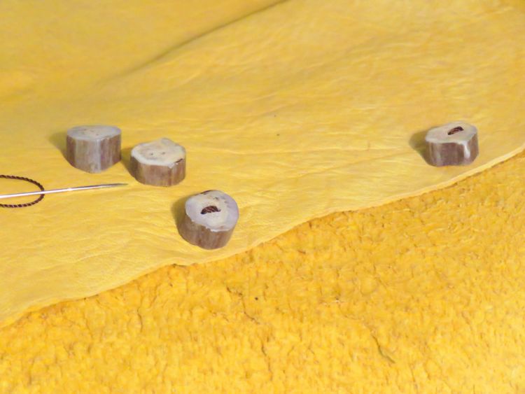 Drill two holes in each button and use thread to secure them to a piece of material.