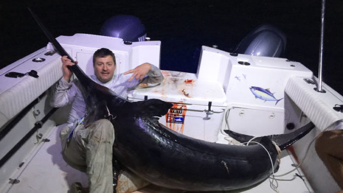 Chris Negulescu poses with the massive 328.4-pound broadbill swordfish he landed along with his nephew, Alex Negulescu, and Eric Hebert, Saturday out of Venice.