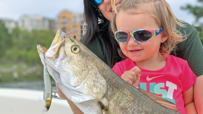 Charleigh Champagne, the 2 1/2-year-old daughter of Matrix Shad owner Chas Champagne, admires a huge speckled trout that fell for a Matrix Rip Shad.
