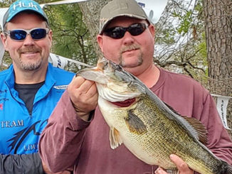 Jason Fails holds his nearly 12 pound win-win-win lunker largemouth as partner and net man David Gordon looks on.