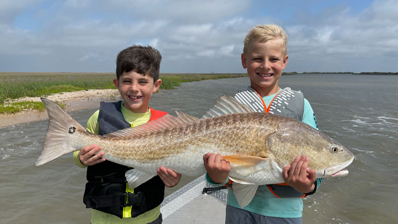 Hayes Thibodeaux, 8, and Ashton Toups, 8, with a 40-inch bull redfish caught at Pecan Island while relaxing on the water during Easter break.