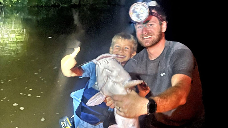 Jase LeBlanc and his dad Derek Leblanc with a catfish caught during nighttime noodling in Manchac, La.